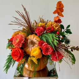Autumn floral arrangement in a pumpkin container with roses and mums