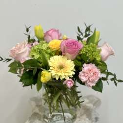 Mixed pink and yellow flowers arranged in a glass vase