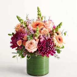 Pink and peach flowers arranged in a green vase