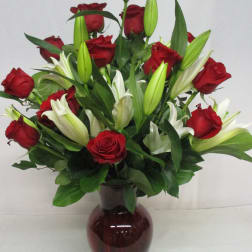 Red roses and white lilies arranged in a dark glass vase