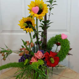 Colorful floral arrangement with sunflowers, roses, and a pink heart accent
