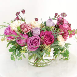 Pink and lavender roses with carnations in a glass vase