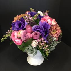 Pink and purple mixed bouquet in a white pedestal vase