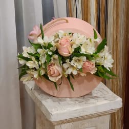 Pink roses and white lilies arranged in a round pink box