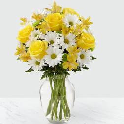 Yellow roses and white daisies in a clear glass vase