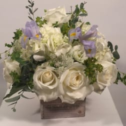 White rose and hydrangea arrangement with lavender irises in a wooden box
