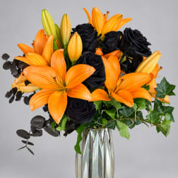 Orange lilies and black roses in a clear glass vase