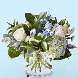 White roses and blue hydrangea in a clear glass vase