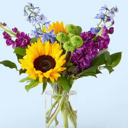Sunflower bouquet with purple and blue flowers in a glass vase