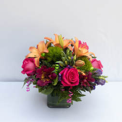 Bouquet of pink roses and orange lilies in a square glass vase
