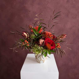 Mixed floral arrangement with red roses in a patterned vase