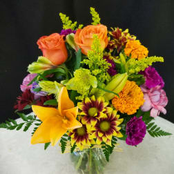 Mixed bouquet of roses, lilies, and chrysanthemums in a glass vase