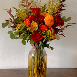 Red and orange flower bouquet in a glass vase