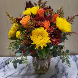 Mixed bouquet of yellow chrysanthemums and orange roses in a glass vase