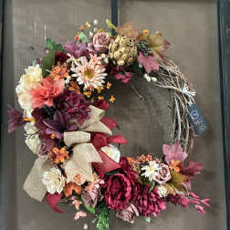 Floral wreath with pink, burgundy, and cream blooms on a twig base
