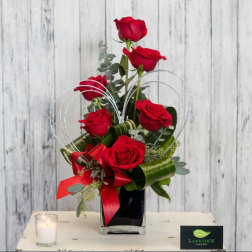 Red roses arranged in a black vase with a red ribbon