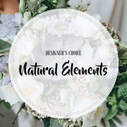 White floral arrangement with a round "Designer’s Choice Natural Elements" sign