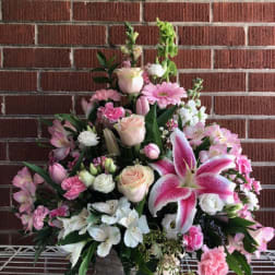 Pink and white mixed flower arrangement in a white basket vase
