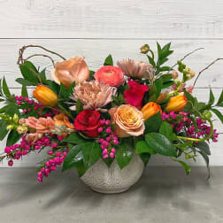 Mixed bouquet in a white ceramic vase with pink, peach, and orange flowers