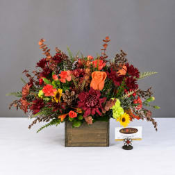 Autumn floral arrangement in a wooden box with orange and burgundy blooms