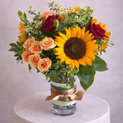 Bouquet of sunflowers and roses in a glass vase with a ribbon