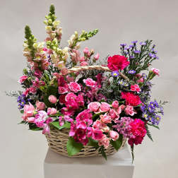Basket arrangement of pink flowers with purple accents