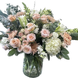 Blush roses and pale flowers in a clear glass vase