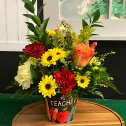 Colorful mixed flower arrangement in a teacher-themed pot