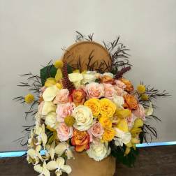 Large bouquet of roses and orchids in a tan hatbox