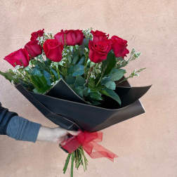 Bouquet of red roses wrapped in black paper with a red ribbon