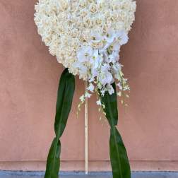 Heart-shaped white rose standing spray with orchids and long green leaves