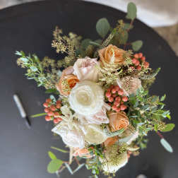 Bouquet of peach and white roses with berries and greenery