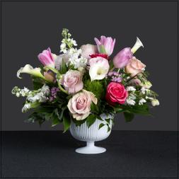 Pink and white floral arrangement in a white pedestal vase