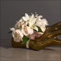 White roses and orchids arranged on a gold hand sculpture