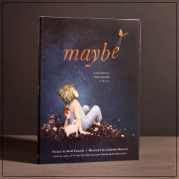 A hardcover book titled "maybe" stands upright on a table.