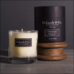 Two scented candles, one in a glass tumbler and one in a black tin box