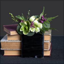 Green and white flowers in a black ribbon wrap on stacked books