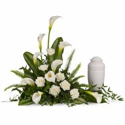 White calla lilies and roses arranged beside a white urn