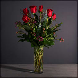 Red roses in a clear glass vase with small pink filler flowers