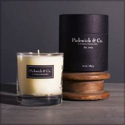 Glass candle with black labeled box on a wooden spool