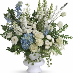 White and blue floral arrangement in a white urn vase