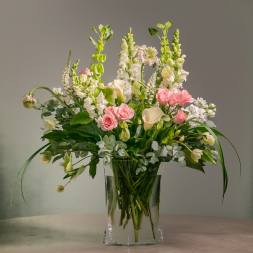 Pink roses and white flowers in a clear glass vase