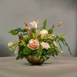 Mixed floral arrangement in a gold bowl with pale pink and white blooms