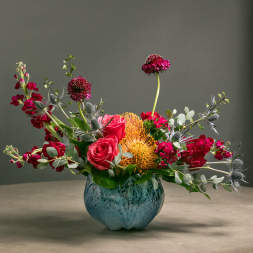 Mixed bouquet of red and pink flowers in a blue vase