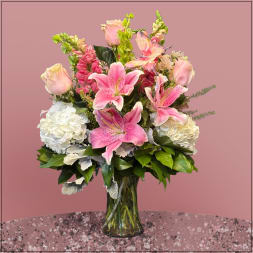 Pink lilies and white hydrangeas arranged in a clear glass vase
