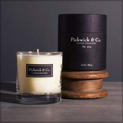 Glass candle in a clear tumbler with a black branded box behind it