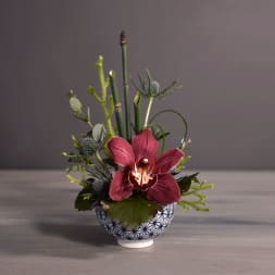 Small orchid arrangement in a patterned ceramic bowl