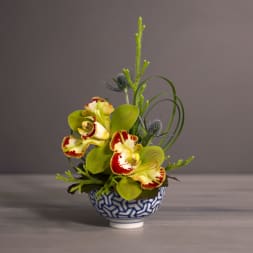 Small floral arrangement in a blue-and-white patterned bowl with yellow-red orchids