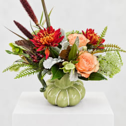 Bouquet of peach and red flowers in a green pumpkin-shaped vase