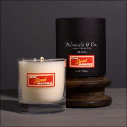 Two branded candles, one in a glass tumbler and one in a black tin